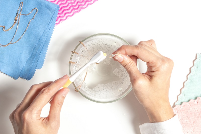 Cleaning gold jewellery with toothbrush