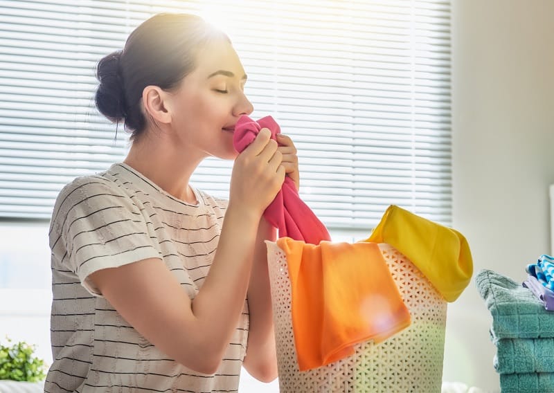 Woman smelling cloths while doing laundry