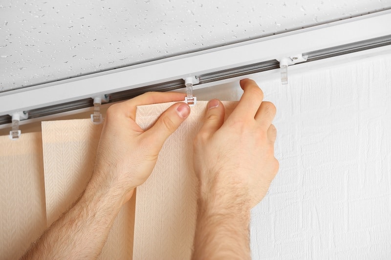 male hands installing vertical blinds