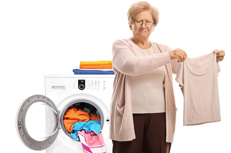 Upset woman holding blouse shrunk by washing machine