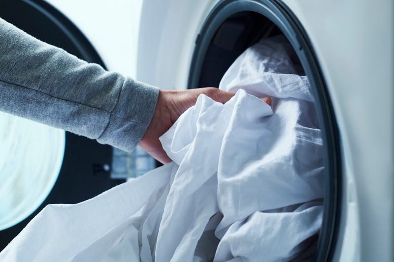 Man putting sheets in washing machine