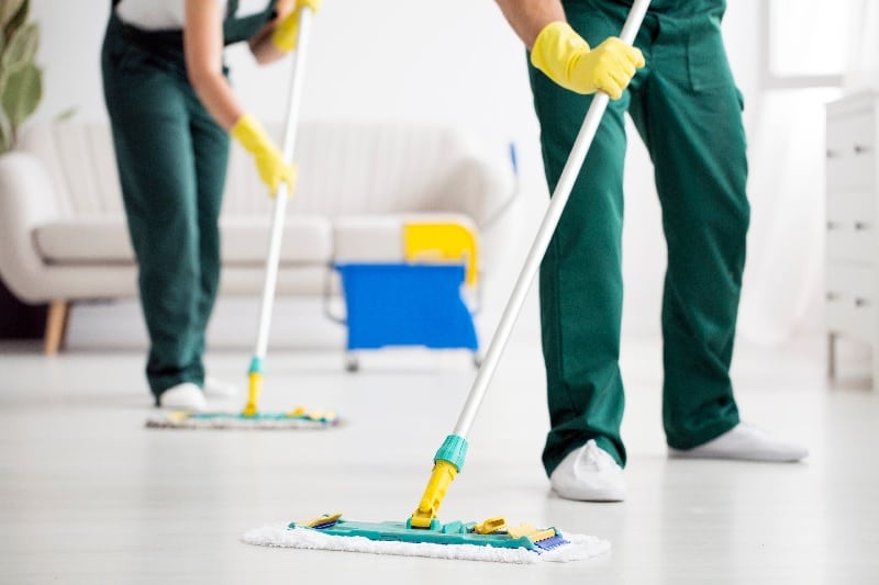 Professional cleaners mopping floor in living room