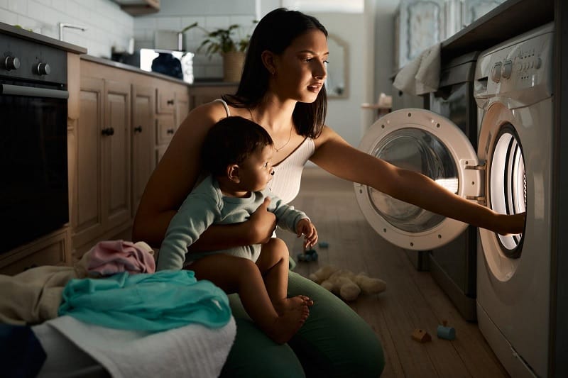 Woman doing laundry with baby