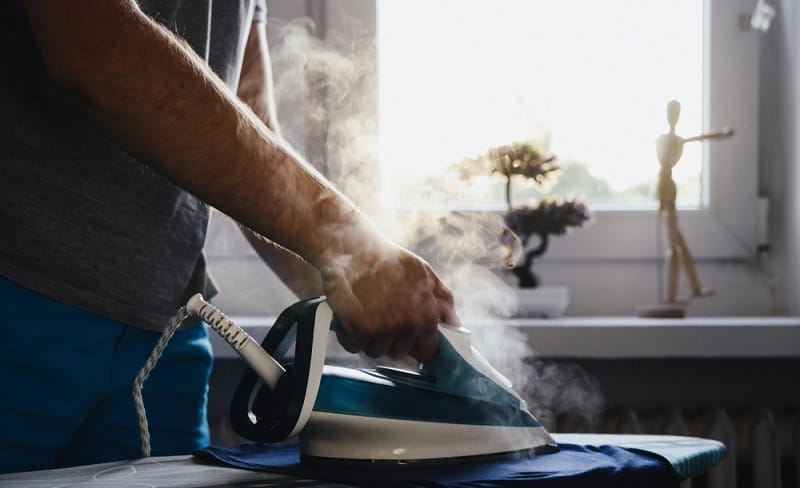 Man using a steam iron to iron clothes