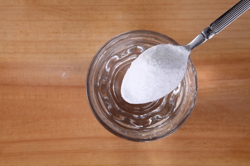 Putting spoon of bicarbonate of soda into glass