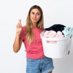 Woman with laundry basket crossing fingers