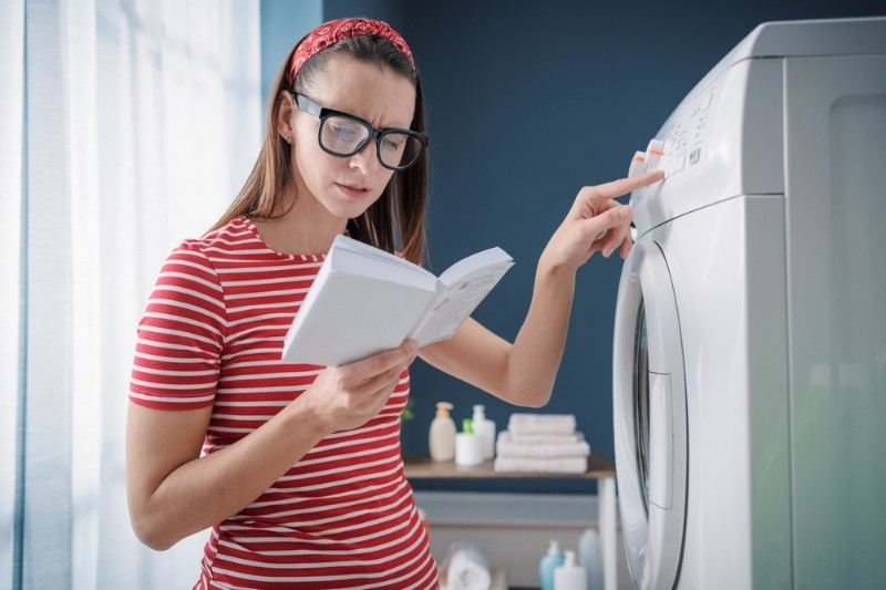 woman reading manual of new washing machine