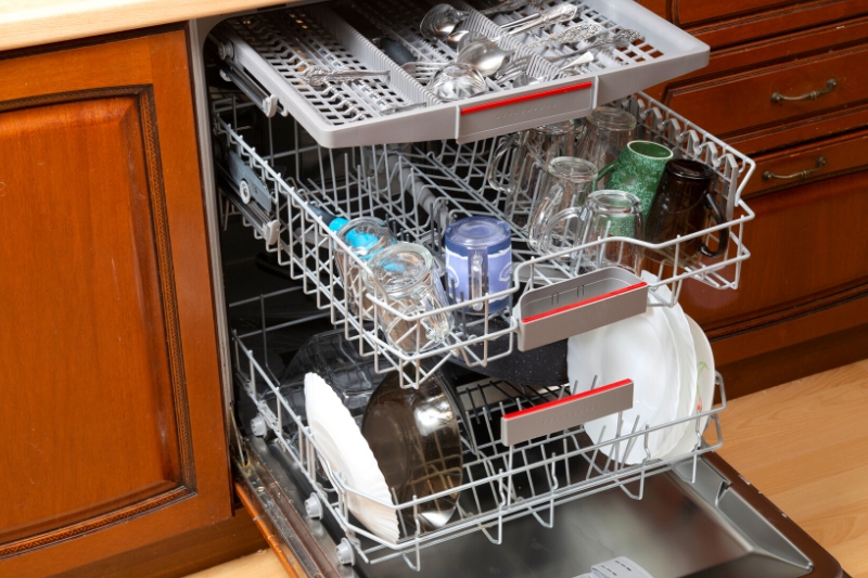 an open dishwasher with some dishes