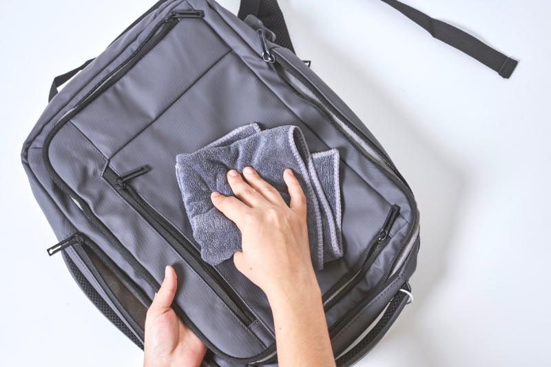 hand wiping backpack with cloth