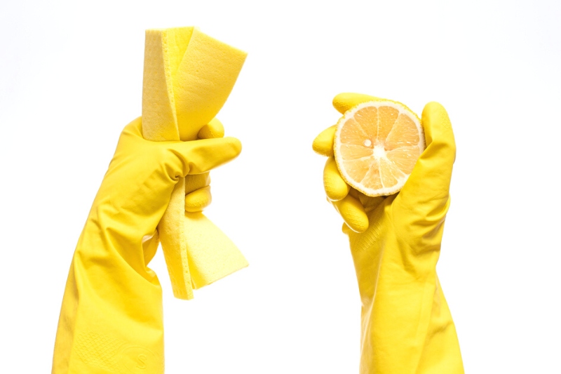 hands with cleaning gloves, cloth and sliced lemon