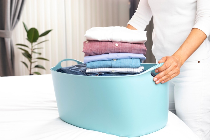 woman holding laundry basket with folded clothes
