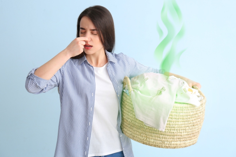 woman holding smelly laundry