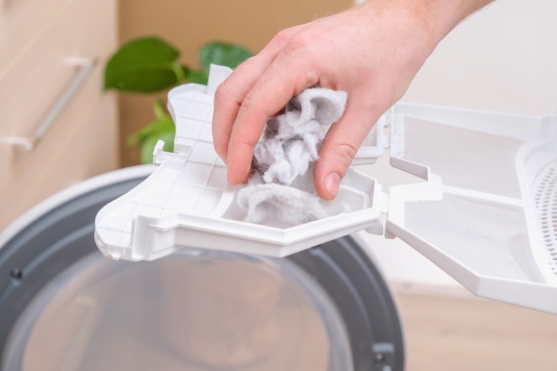 hand removing lint from tumble dryer lint filter