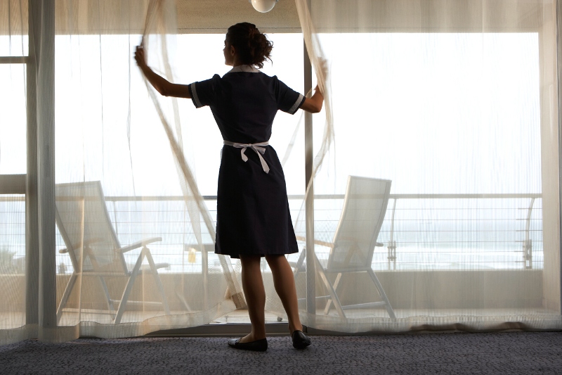 maid adjusting sheer curtains