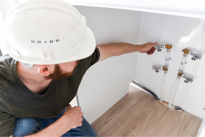 worker checking water pipes for washing machine