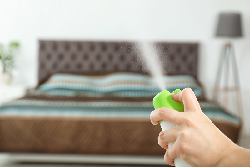 Spraying air freshener in bedroom