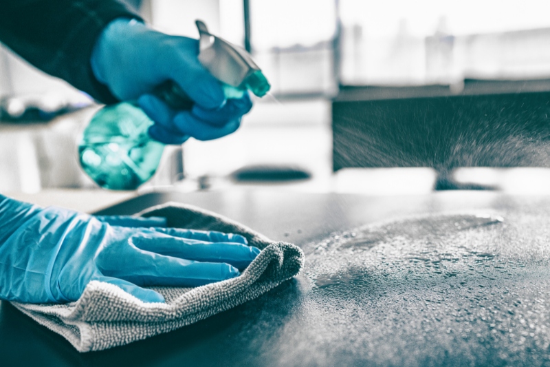 cleaning table with cloth and disinfectant spray