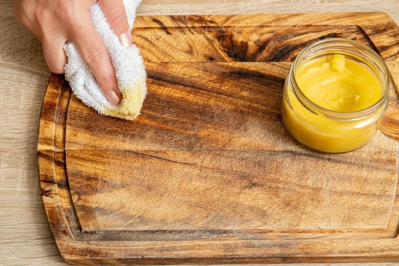 Applying beeswax to wood chopping board