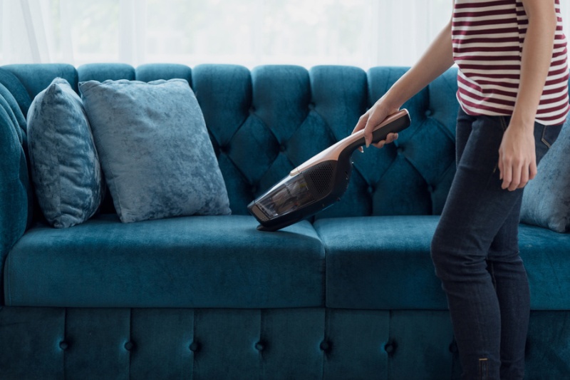 woman vacuuming velvet sofa