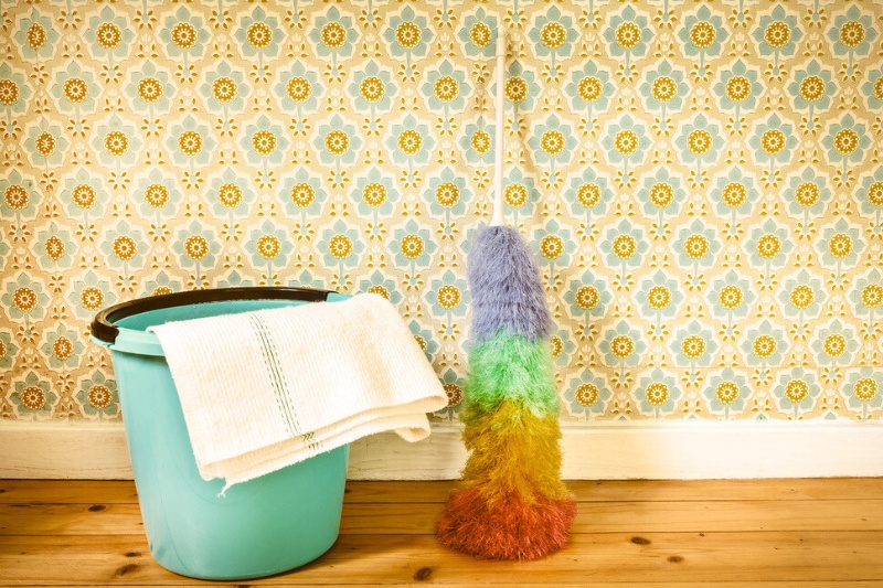 bucket with cleaning cloth and feather duster behind wallpaper