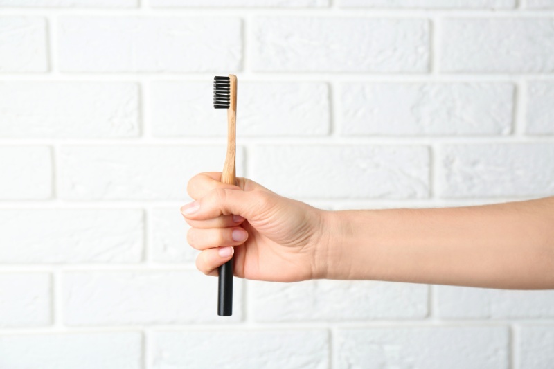 hand holding toothbrush with brick wall background
