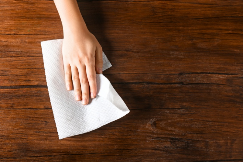 wiping wooden table with kitchen towel