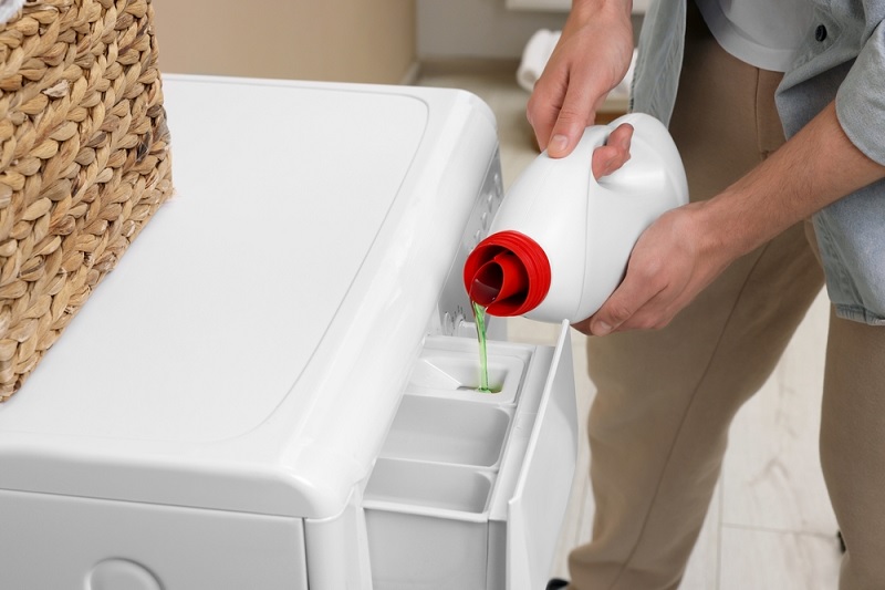 Pouring laundry sanitiser into washing machine drawer