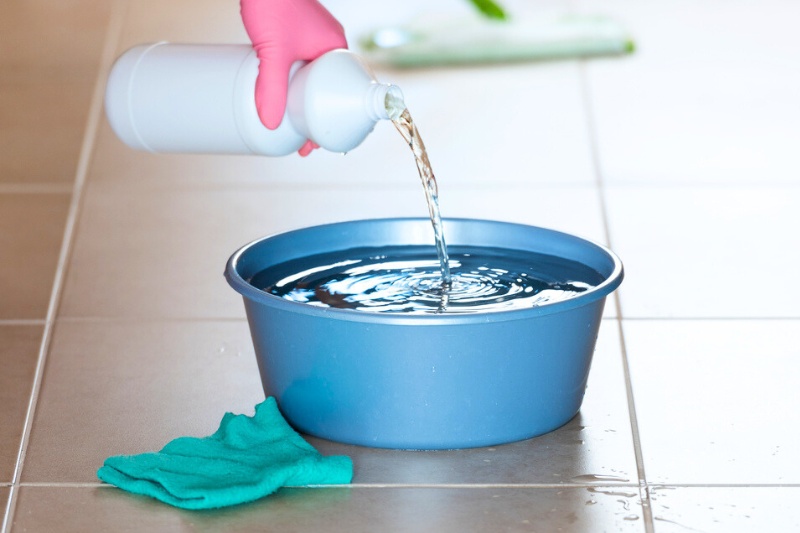pouring bleach into bowl with water