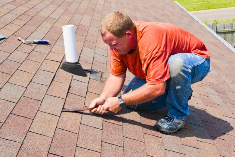 man repairing roof shingles