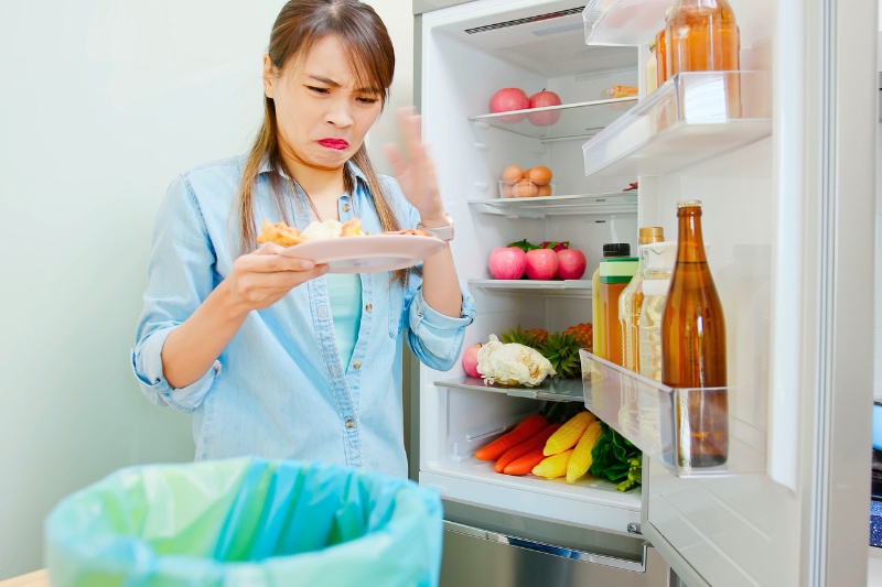 woman holding smelly food from the fridge