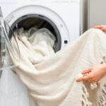 woman holding white blanket in the washing machine
