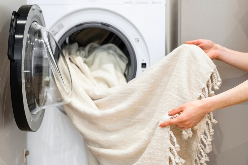 woman holding white blanket in the washing machine