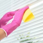 cleaning blinds with cloth and gloves
