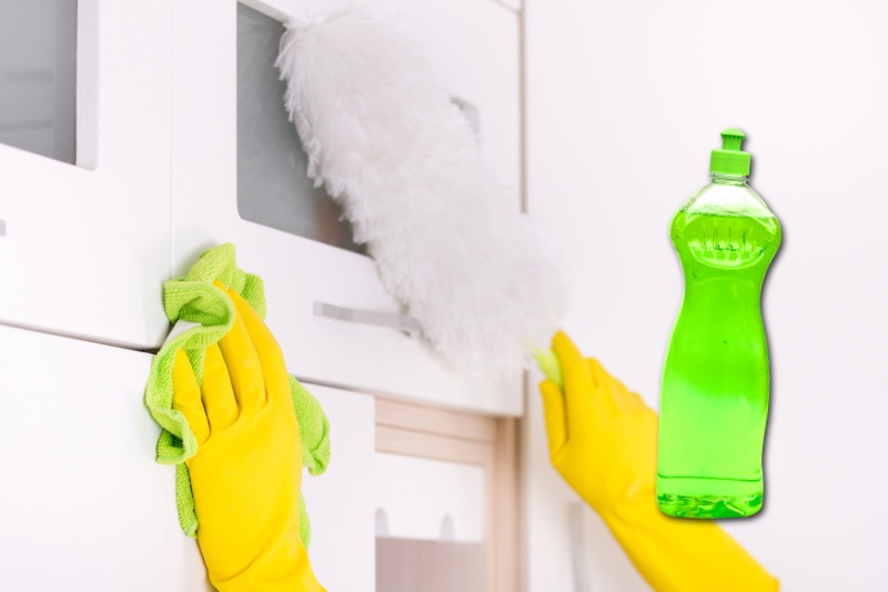 dusting kitchen cabinets with feather duster and cleaning cloth
