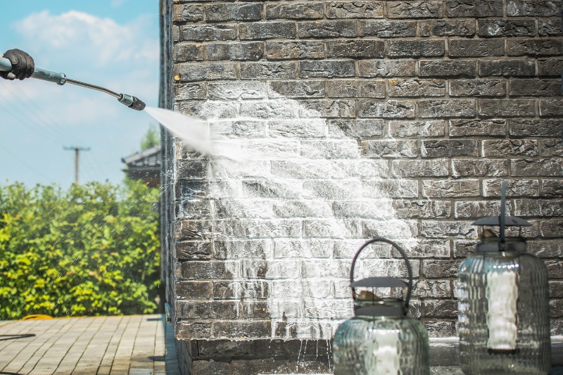 pressure washer with cleaning solution on brick wall