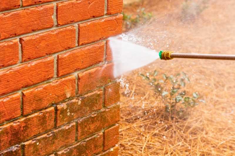 using pressure washer to clean brick wall